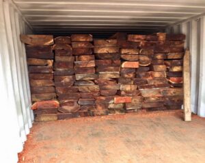 Stacks of African Redwood timber neatly arranged in a shipping container, ready for export